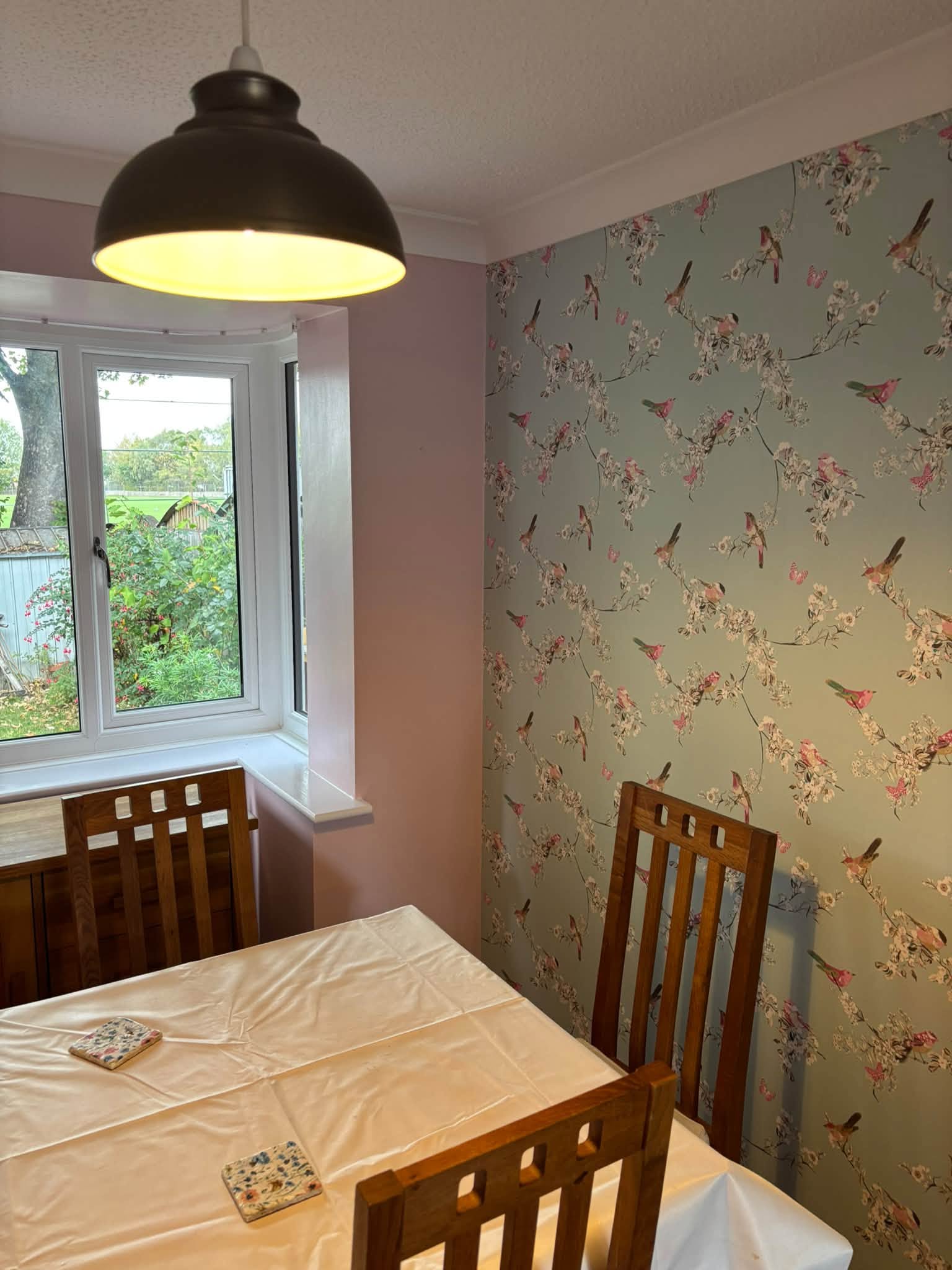 Dining area with pale green wall and coordinating wallpaper